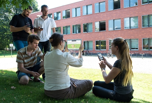 Foto: Studierende im Grünen mit Mobilen Geräten