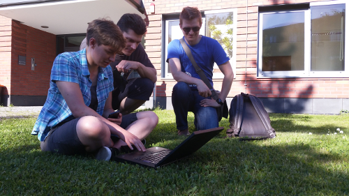 Foto: Studierende im Grünen mit Mobilen Geräten